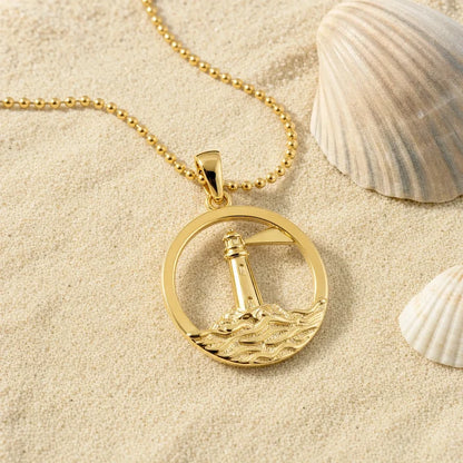 Anhänger Leuchtturm Rund / Küste vergoldet, goldene Kette auf Sand mit Muscheln.
